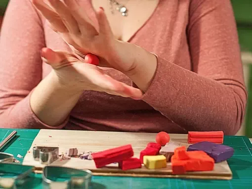 Photo d'une femme faisant une boule d'argile polymère entre ses mains