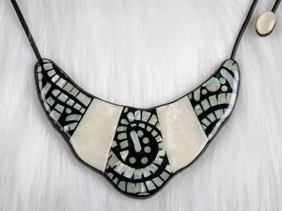 Le collier Indira est modulable il est réversible et réglable en longueur sur son recto on retrouve un superbe assemblage d'imitation nacre et de mosaïque ses finitions en font un produit de bijouterie de luxe